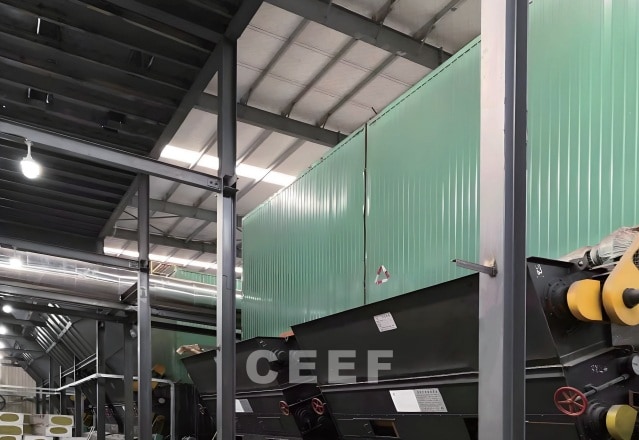 Green-clad CEEF thermal oil heater with fuel feeding conveyors inside an Intco Medical glove factory