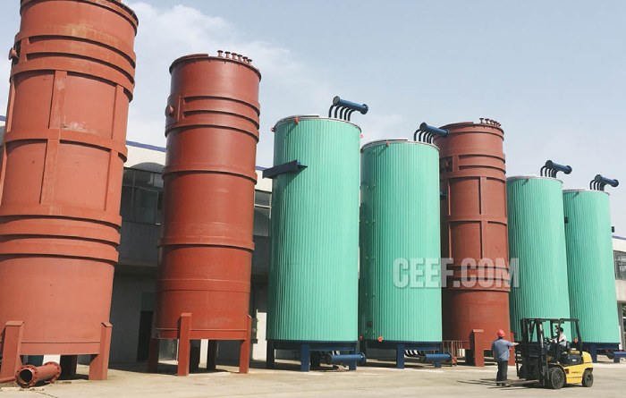 Seven large vertical CEEF thermal oil heaters lined up at the factory, with a forklift for scale